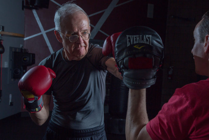 Elderly man boxing with a coach