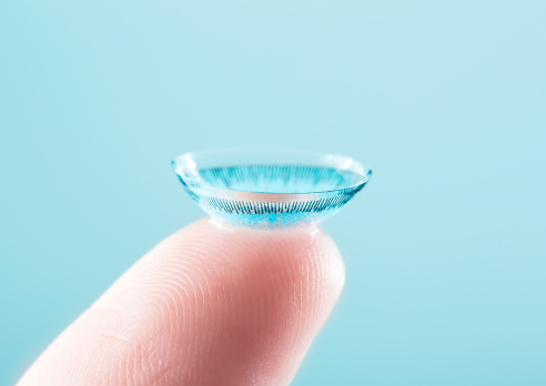 A blue contact lens on a finger