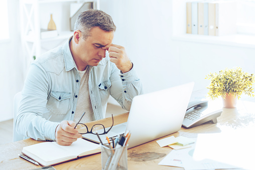 Man sitting at a desk and feeling stressed about his laptop