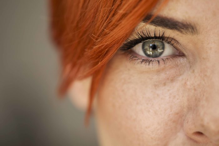 Close up of a woman's grey/green eye and ginger hair