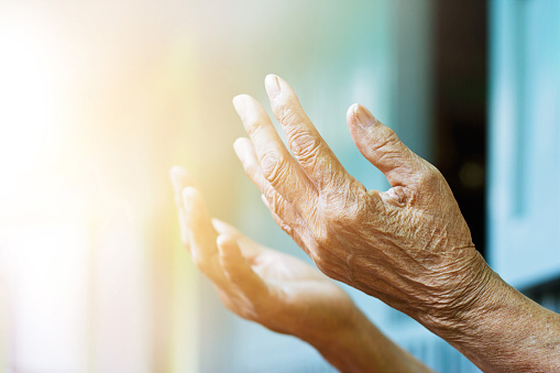 Elderly hands lifting up to a light