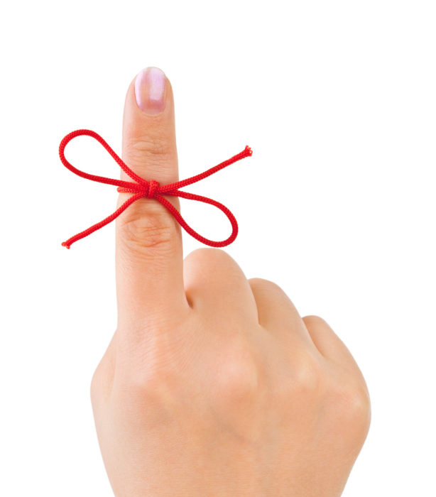 An index finger with a red string tied around it