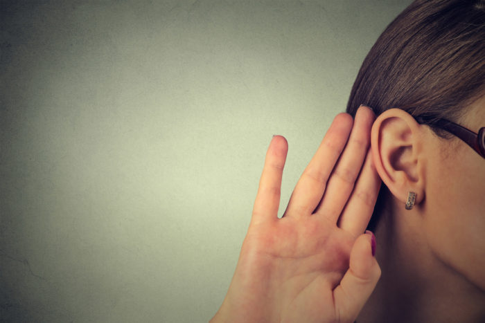 A woman cupping her ear to hear better