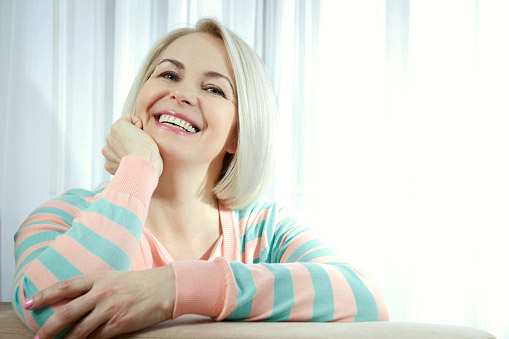 A woman with platinum hair and a pink and blue stripy top smiling