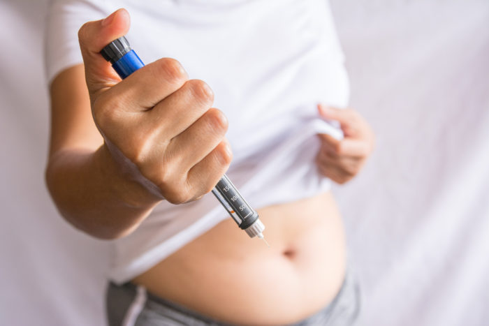 A person holding up an EpiPen, getting ready to inject into their stomach