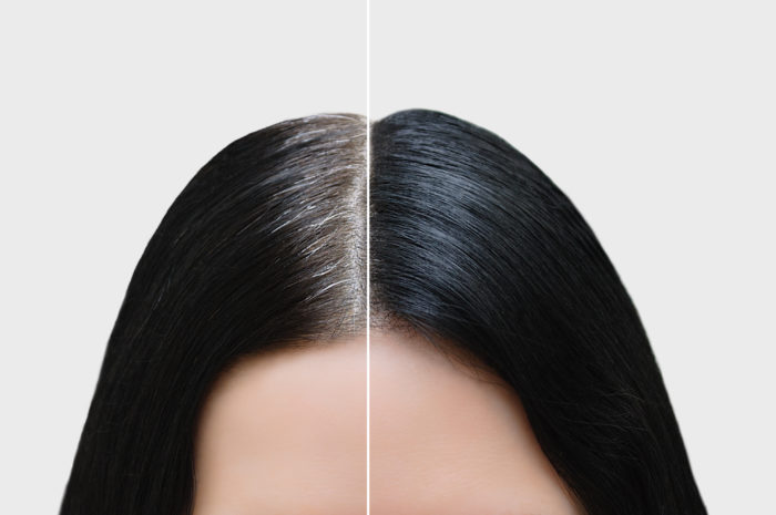 A woman's hair split down the middle with half showing grey hairs