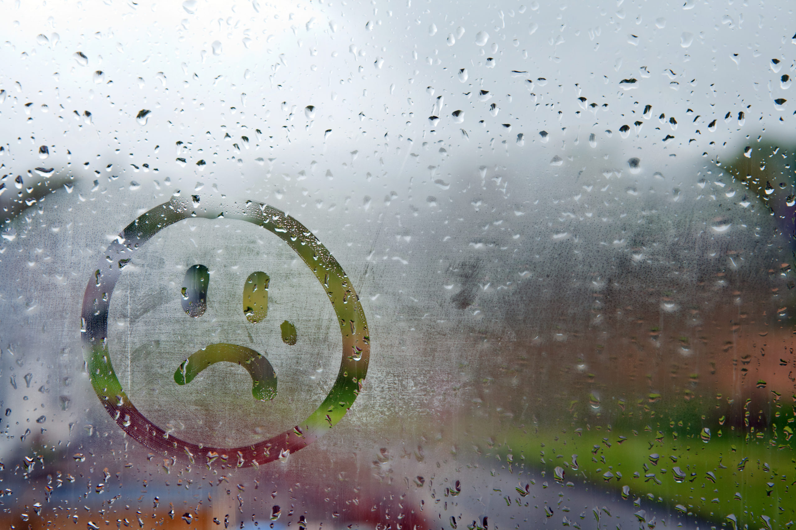 Window with a sad face drawn in the condensation