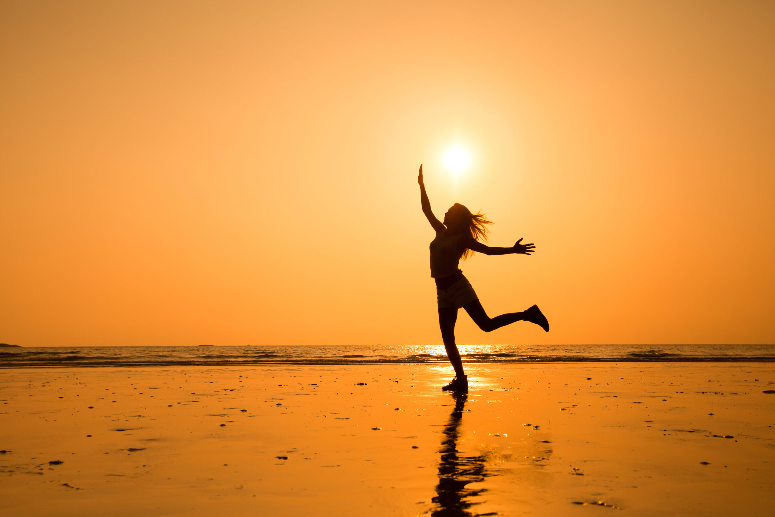 Woman jumping on the beach Infront of the sunset