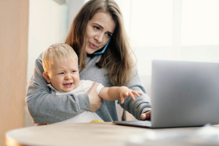 Lady holding baby near laptop