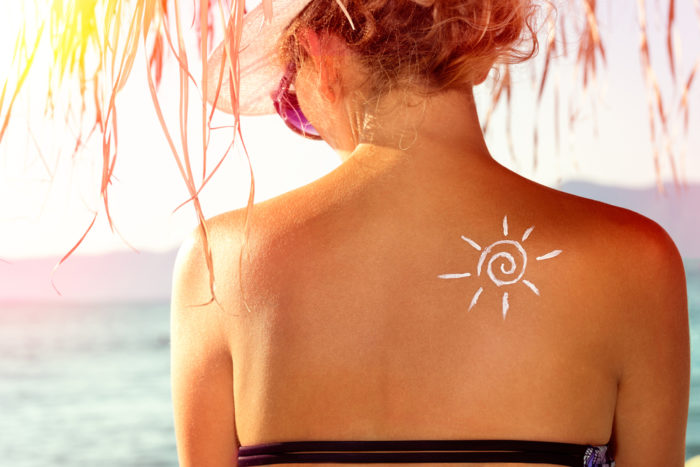 Woman with sun in sunscreen pattern on her back