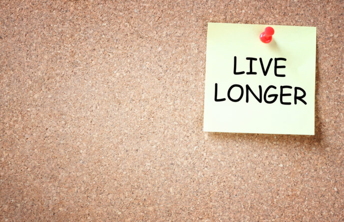Sticky note pinned on a cork board with the text 'Live Longer'