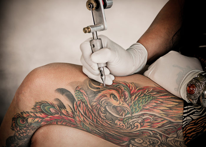Somebody tattooing a leg with a tattoo gun