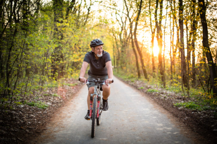 A man riding his bike down a track surrounded by trees