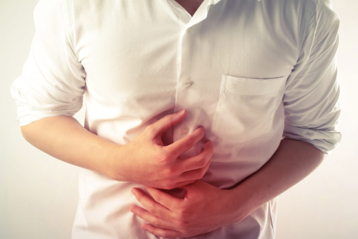 Person in a white shirt in pain with their stomach