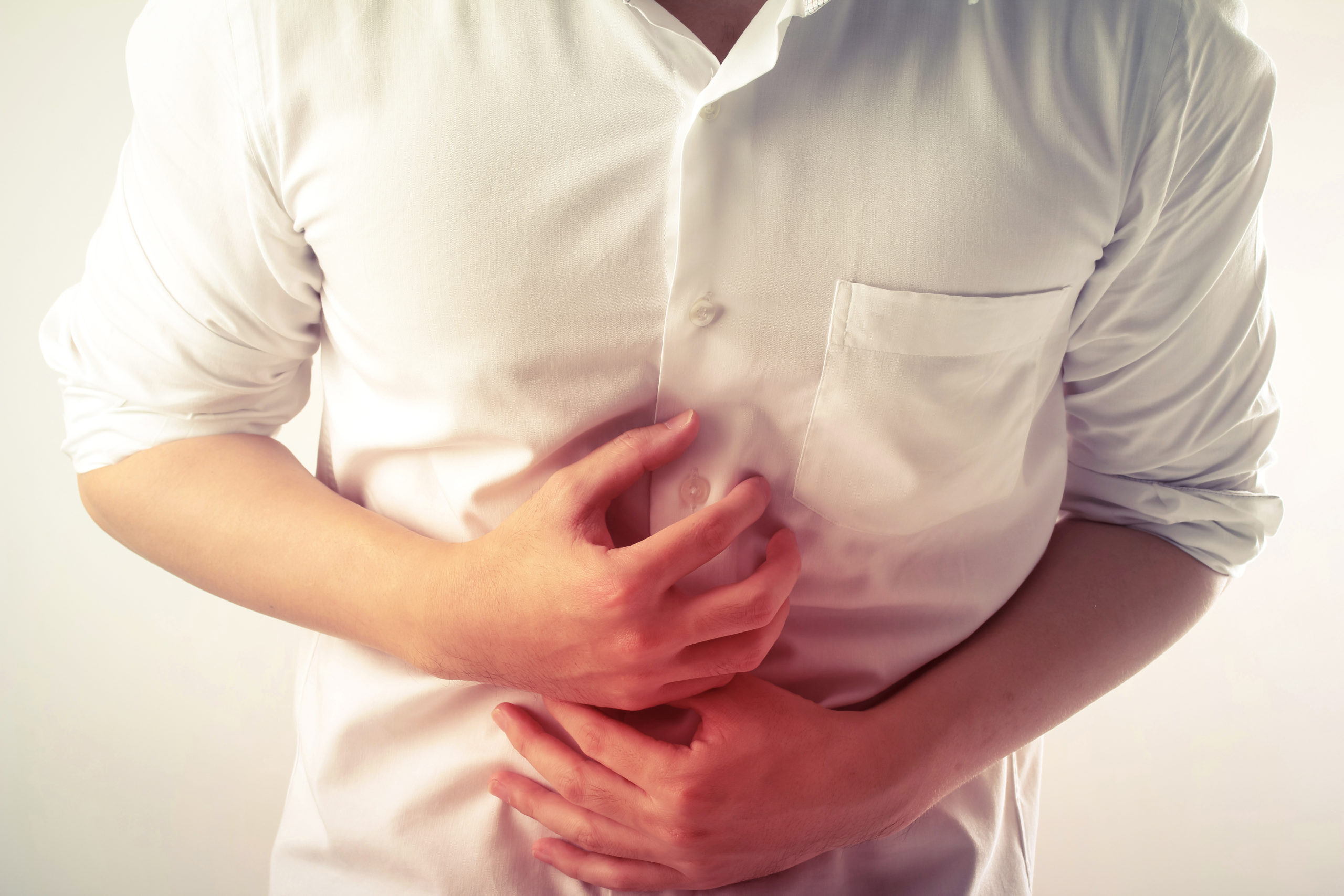 Person in a white shirt in pain with their stomach