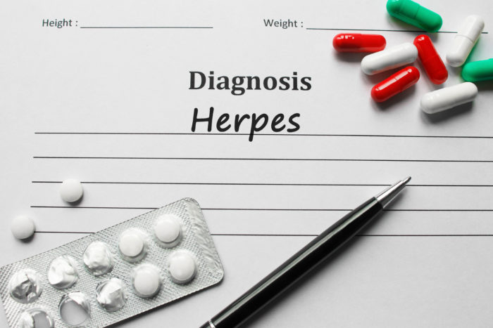 Herpes Diagnosis written down on paper surrounded by pills